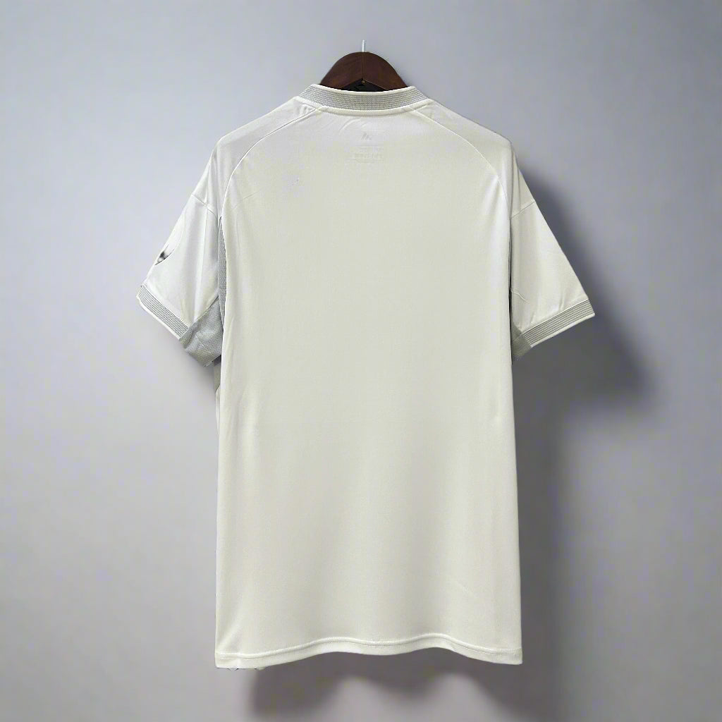 White t-shirt hanging on a black metal frame against a geometric patterned wall.