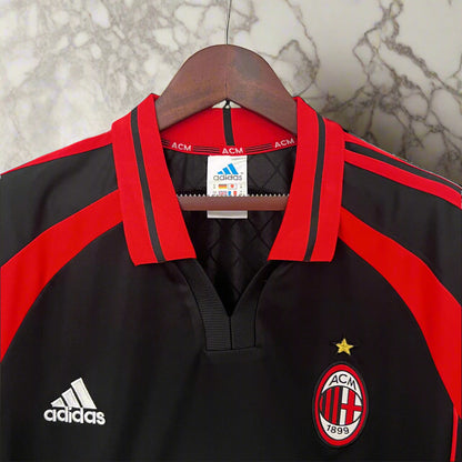 Black and red sports jersey with Adidas logo on a hanger against a chain-link fence background