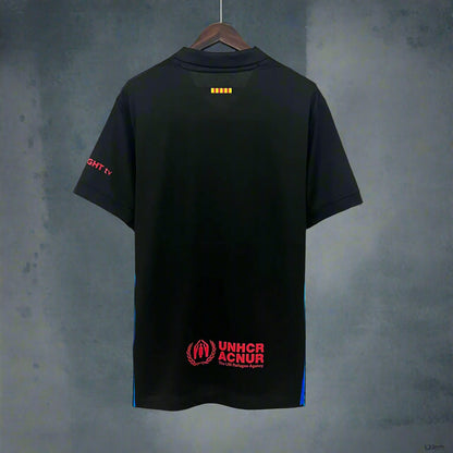 Black Barcelona jersey with red text and logos on a hanger against a geometric background