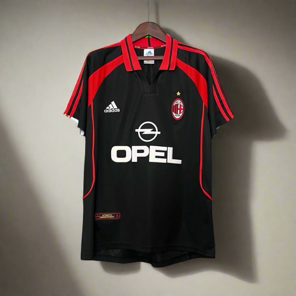 Black sports jersey with red accents, featuring Adidas and Opel logos, on a hanger against a grid background.