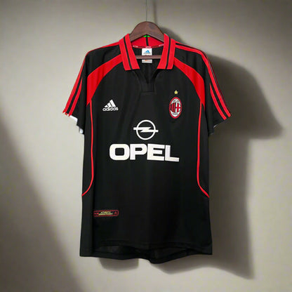 Black sports jersey with red accents, featuring Adidas and Opel logos, on a hanger against a grid background.