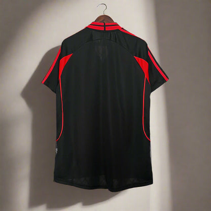 Black shirt with red accents on a metal stand against a grid background